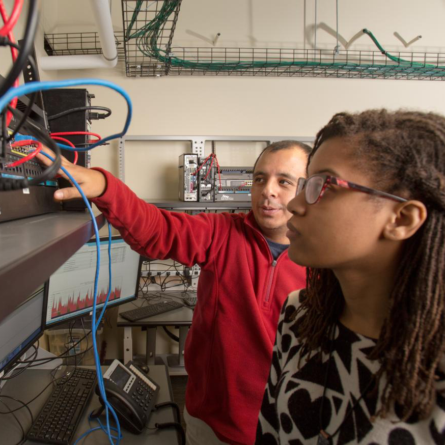 Mentor and student looking at wires and equipment.