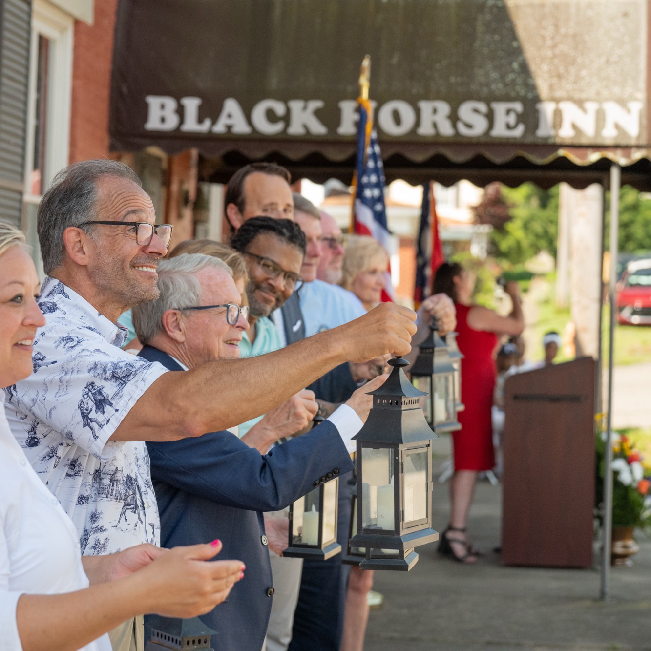 Group gathered with Governor DeWine holding black lanterns infront of Black Horse Inn..