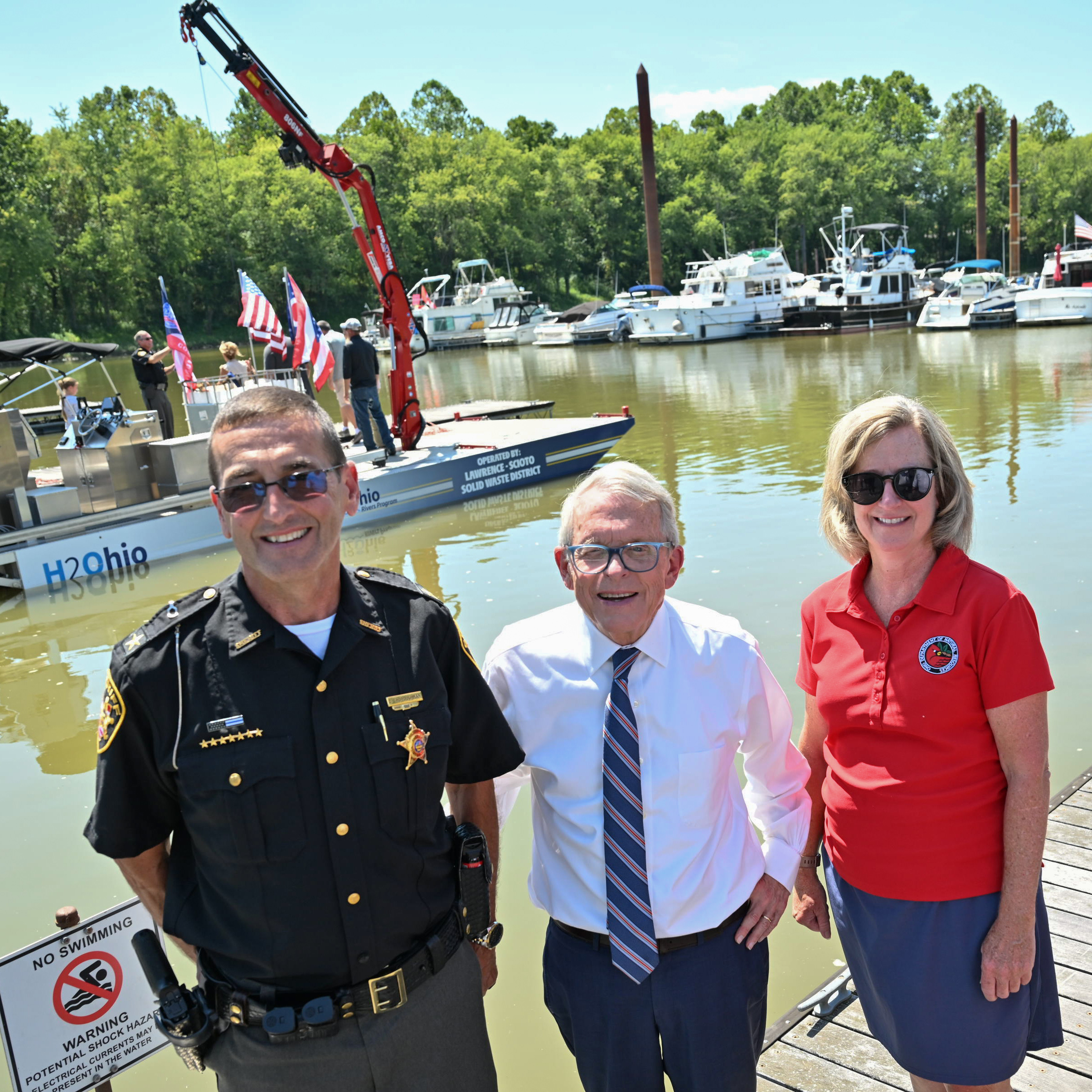 Governor DeWine and ODNR Director Mary Mertz stand infant of H2Ohio Barge with law enforcement officer.
