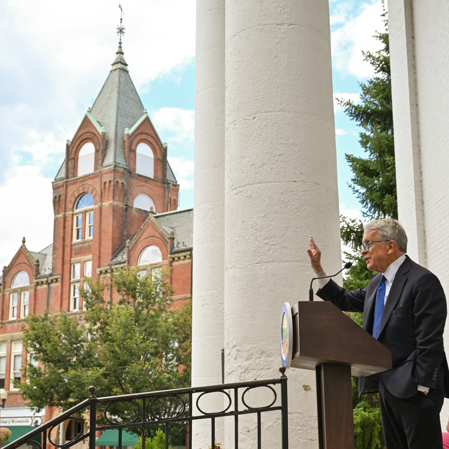 Governor Dewine speaking with McConellsville courthouse in background.
