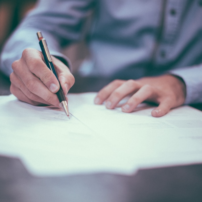 Writing with a pen on paper at a desk.